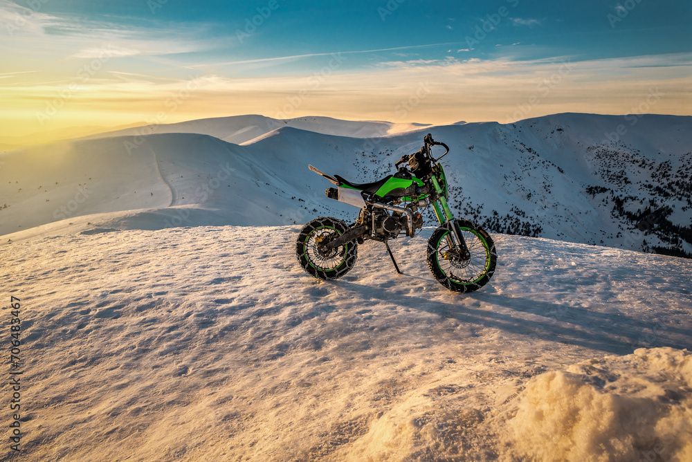 Extreme cross sport motorcycle in winter snowy mountains at sunset Extreme cross sport motorcycle in winter snowy mountains at sunset