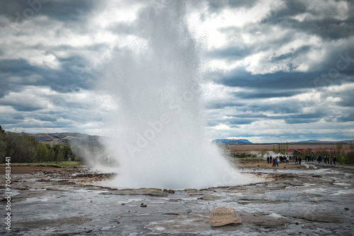 Famous Strokkur fountain geyser hot water eruption with cloudy sky and surrounding Icelandic landscape, Iceland