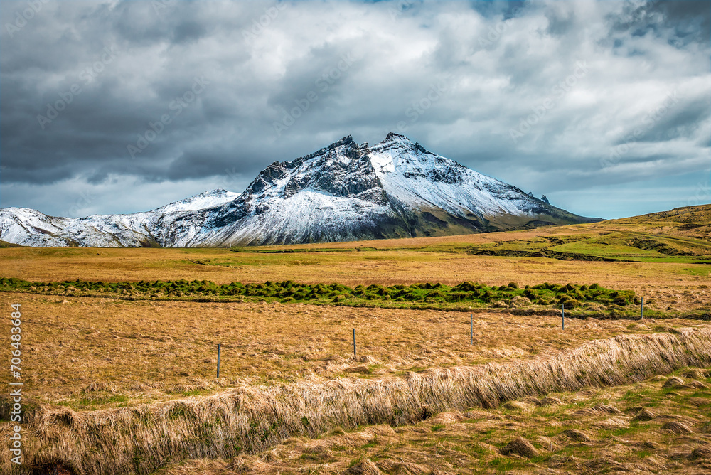 Iceland landscape with rocky snowy mountain and dry grass field