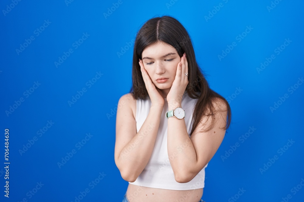 Young caucasian woman standing over blue background tired hands covering face, depression and sadness, upset and irritated for problem Young caucasian woman standing over blue background tired hands covering face, depression and sadness, upset and irritated for problem
