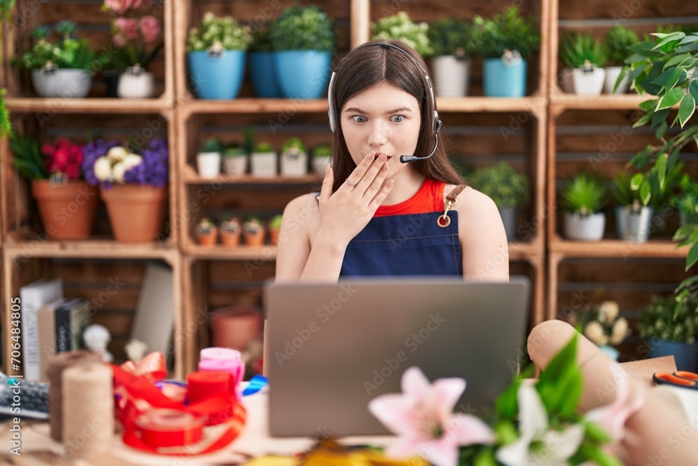 Φωτογραφία Young caucasian woman working at florist shop doing video call covering mouth with hand, shocked and afraid for mistake