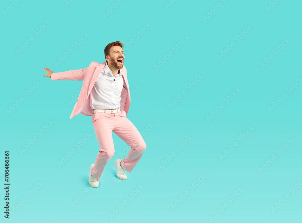 Happy funny man in stylish pink suit dancing on bright blue color copy space background looking at empty blank copyspace side, asking for attention, screaming, advertising sale, inviting to cool party Happy funny man in stylish pink suit dancing on bright blue color copy space background looking at empty blank copyspace side, asking for attention, screaming, advertising sale, inviting to cool party