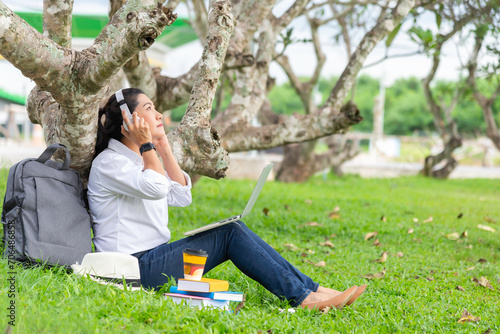 Happy Woman sitting at the park using notebook