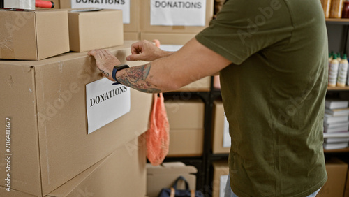 A man in a warehouse organizes boxes labeled donations, implying volunteering or charity work. photo