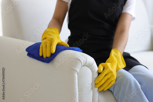 Young Asian woman who cleans the house uses a cloth to clean the sofa in the living room at home.