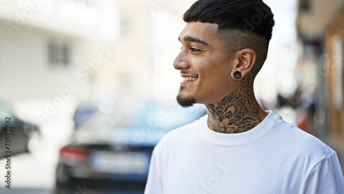 Confident and joyful young latin man, smiling and looking to the side on a bustling city street photo