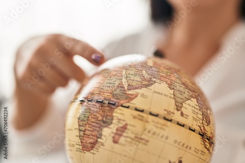 Young beautiful hispanic woman pointing to earth planet with finger at home