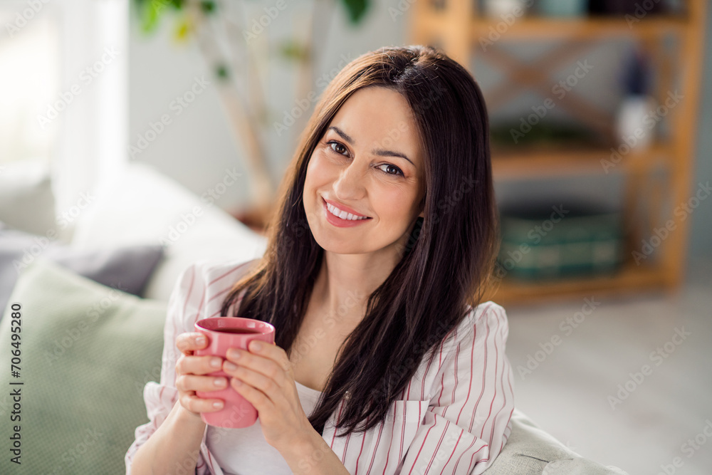 Portrait of positive peaceful girl toothy smile sit sofa arms hold fresh coffee mug enjoy free time house inside Portrait of positive peaceful girl toothy smile sit sofa arms hold fresh coffee mug enjoy free time house inside