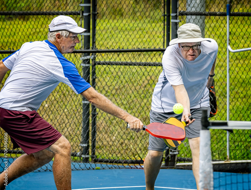 Male doubles teammates both attack the ball during a pickleball tournament © Jo