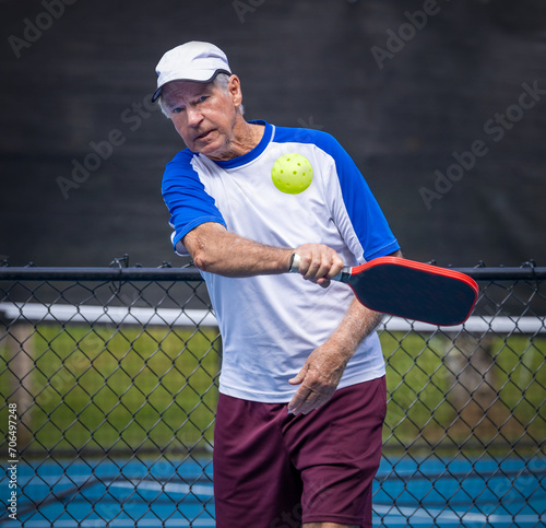 Male senior pickleball player adds topspin to his shot