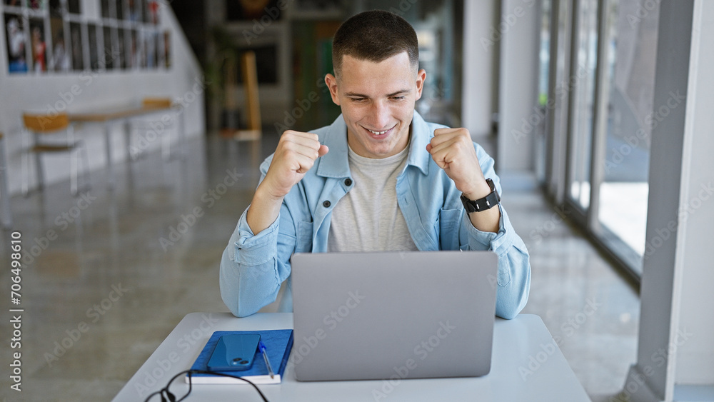 Excited young man with laptop celebrating success at college campus. Excited young man with laptop celebrating success at college campus.