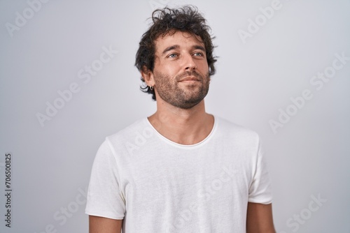Young hispanic man standing looking to the side over isolated white background