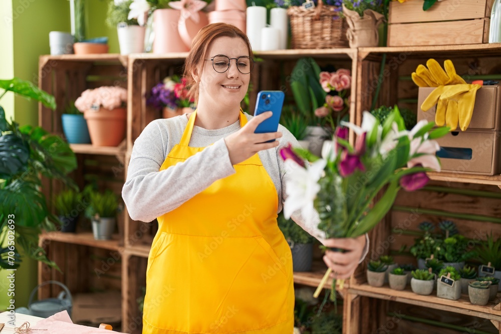 Young beautiful plus size woman florist make photo to bouquet of flowers by smartphone at flower shop