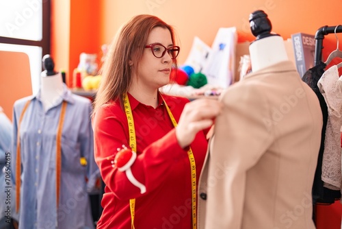 Young beautiful plus size woman tailor standing by manikin working at atelier