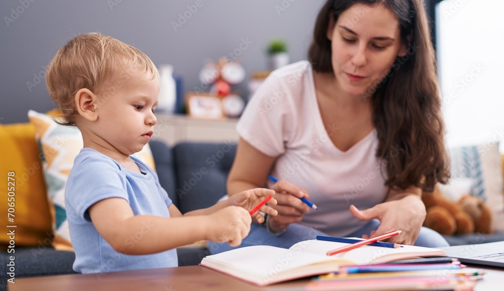 Mother and son sitting on sofa drawing on notebook at home Mother and son sitting on sofa drawing on notebook at home