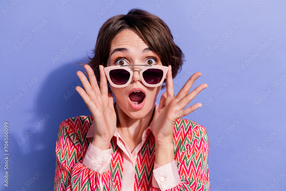 Portrait of speechless girl wear shirt fingers touch stylish sunglass staring at unbelievable sale isolated on blue color background Portrait of speechless girl wear shirt fingers touch stylish sunglass staring at unbelievable sale isolated on blue color background