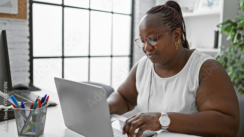 Focused african american woman worker excelling in business. working diligently at her laptop, this boss lady embodies success and professionalism in her office. photo