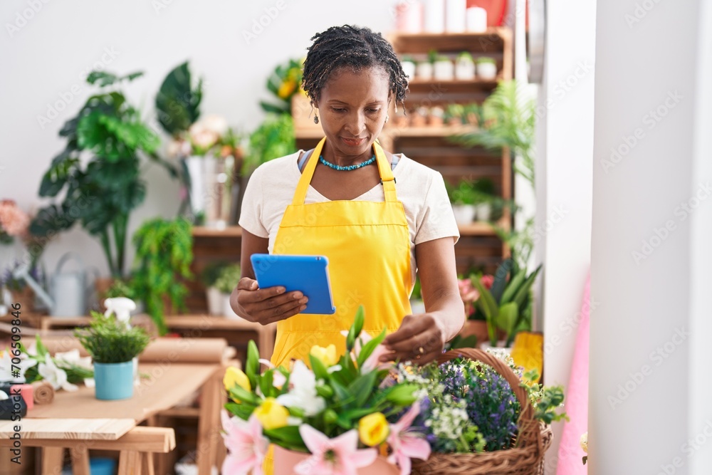 Middle age african american woman florist using touchpad at flower shop Middle age african american woman florist using touchpad at flower shop