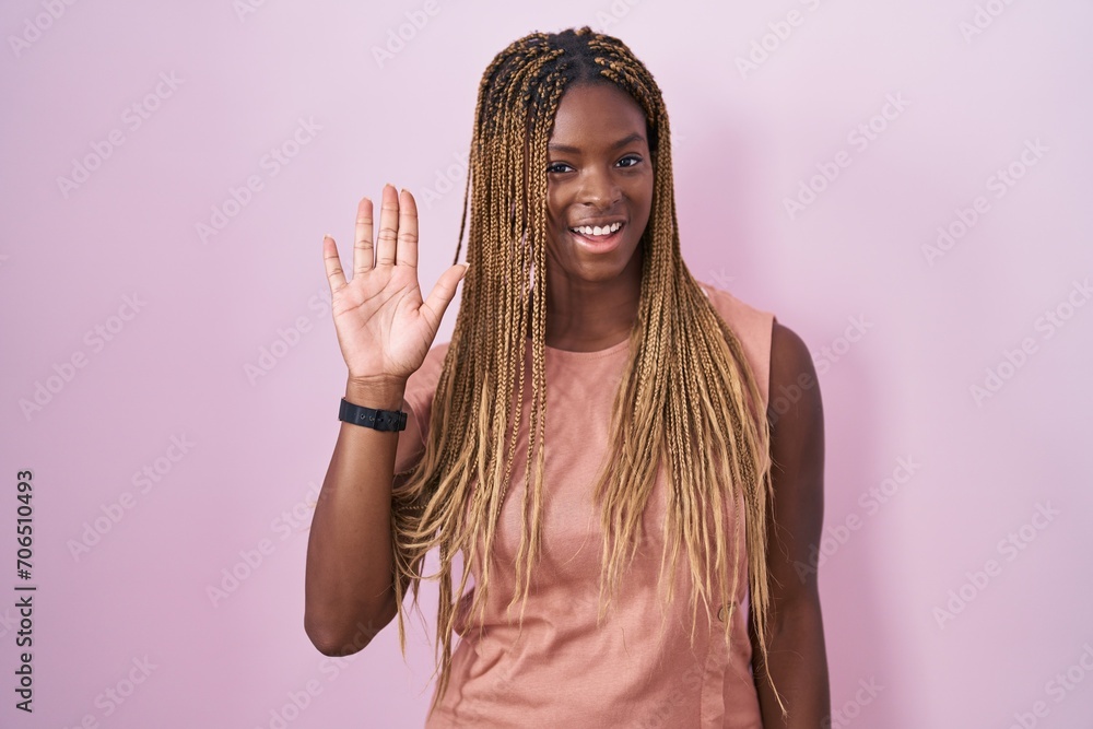 African american woman with braided hair standing over pink background waiving saying hello happy and smiling, friendly welcome gesture African american woman with braided hair standing over pink background waiving saying hello happy and smiling, friendly welcome gesture