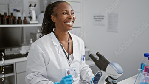 A cheerful woman scientist in a lab coat conducts research in a modern laboratory with microscope and equipment. photo