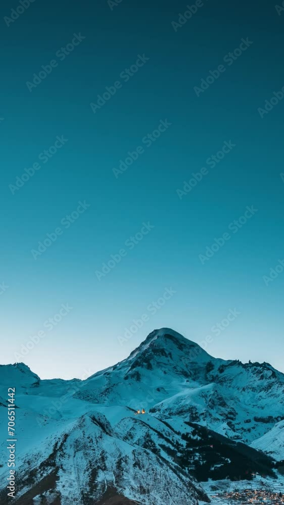 Stepantsminda, Georgia. Winter Night Starry Sky With Glowing Stars Over Peak Of Mount Kazbek Covered With Snow. Beautiful Night Georgian Winter Landscape. Vertical Footage. Stepantsminda, Georgia. Winter Night Starry Sky With Glowing Stars Over Peak Of Mount Kazbek Covered With Snow. Beautiful Night Georgian Winter Landscape. Vertical Footage.