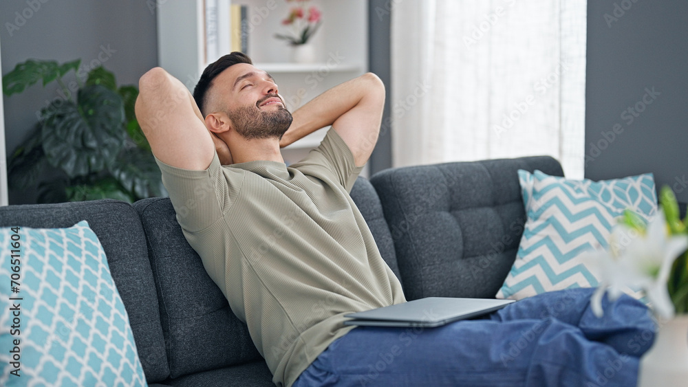 Young hispanic man relaxed with hands on head sitting on sofa at home Young hispanic man relaxed with hands on head sitting on sofa at home