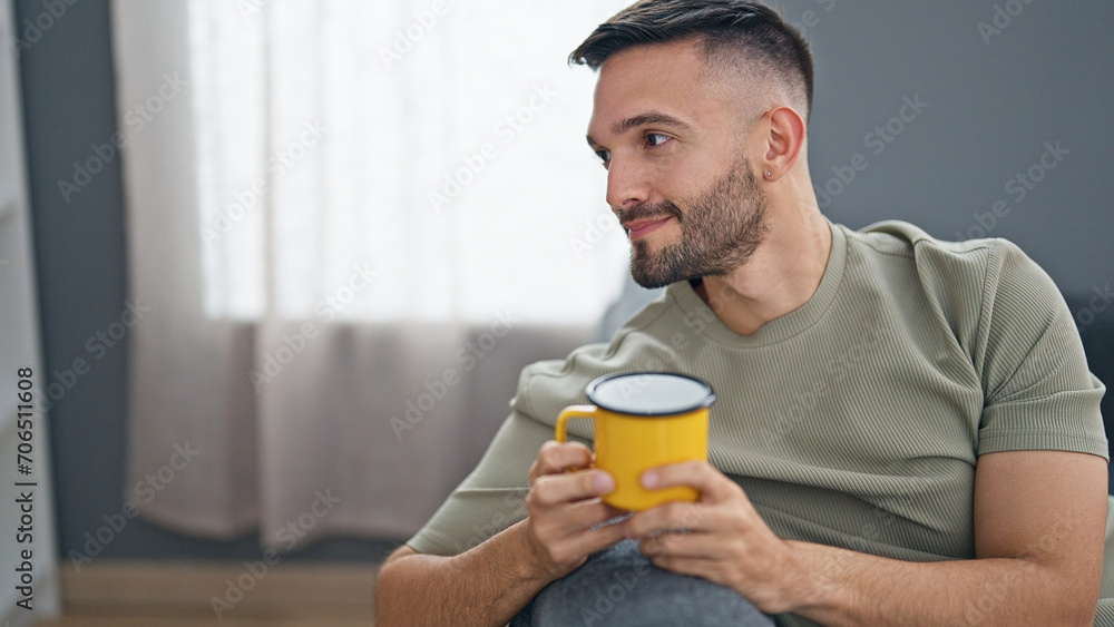 Young hispanic man drinking coffee sitting on sofa at home Young hispanic man drinking coffee sitting on sofa at home