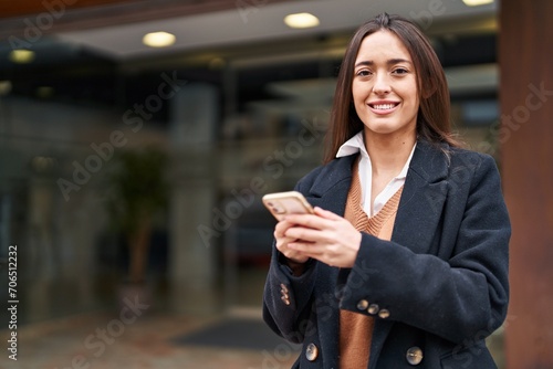 Young beautiful hispanic woman smiling confident using smartphone at street