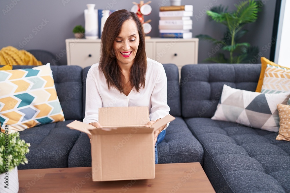 Middle age brunette woman opening cardboard box winking looking at the camera with sexy expression, cheerful and happy face. Middle age brunette woman opening cardboard box winking looking at the camera with sexy expression, cheerful and happy face.
