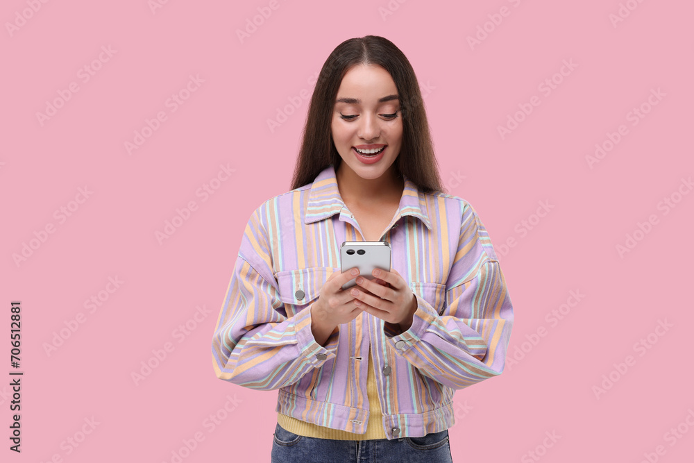 Happy woman sending message via smartphone on pink background Happy woman sending message via smartphone on pink background