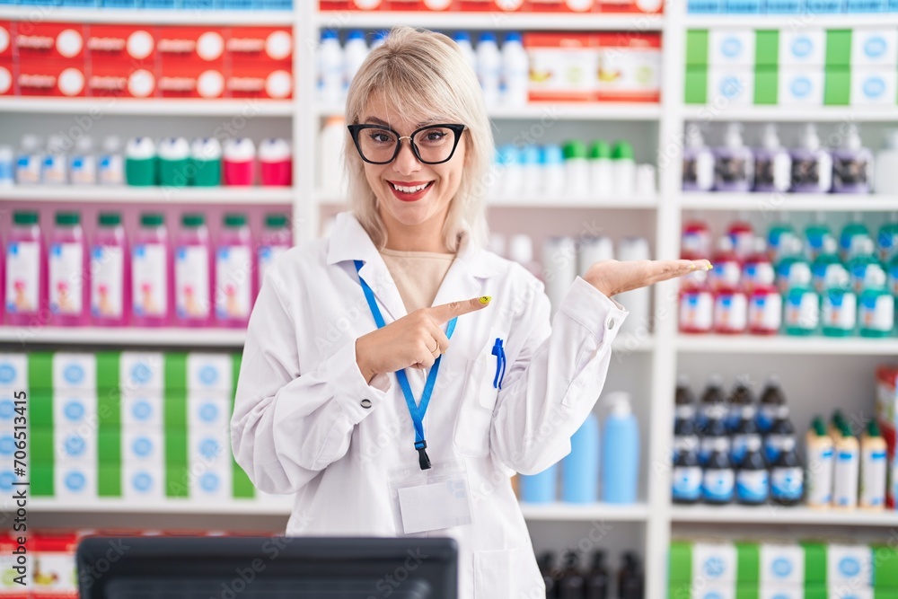 Young caucasian woman working at pharmacy drugstore amazed and smiling to the camera while presenting with hand and pointing with finger. Young caucasian woman working at pharmacy drugstore amazed and smiling to the camera while presenting with hand and pointing with finger.