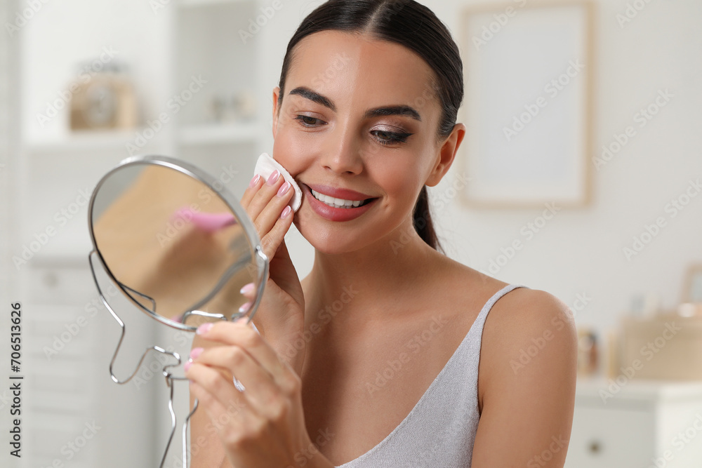 Beautiful woman removing makeup with cotton pad in room Beautiful woman removing makeup with cotton pad in room