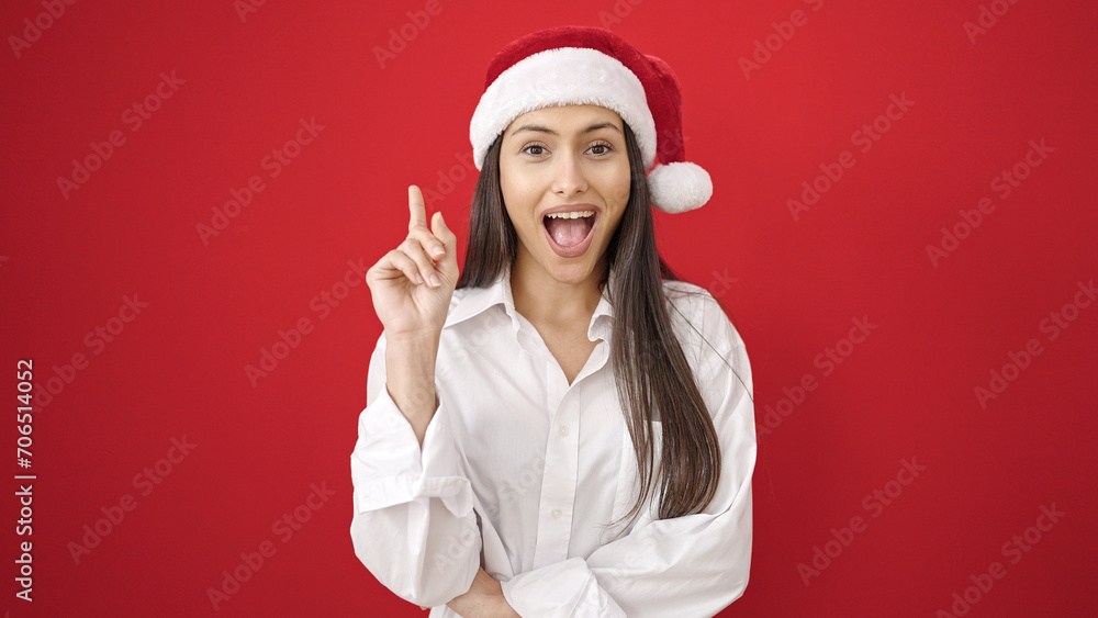 Young beautiful hispanic woman wearing christmas hat with idea expression over isolated red background Young beautiful hispanic woman wearing christmas hat with idea expression over isolated red background