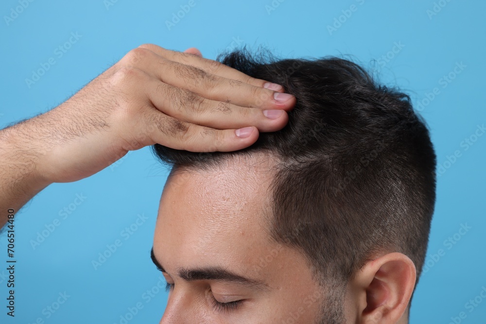 Man examining his head on light blue background, closeup. Dandruff problem Man examining his head on light blue background, closeup. Dandruff problem