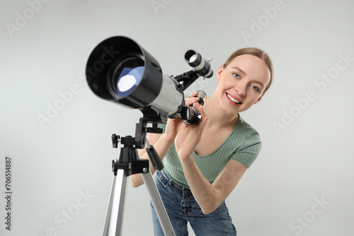 Young astronomer with telescope on grey background