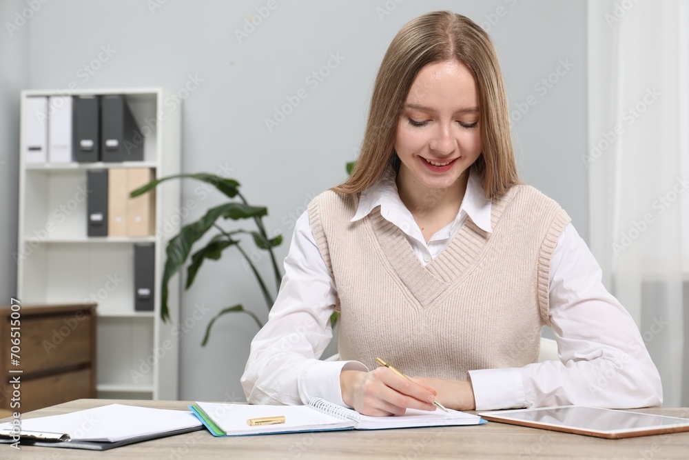 Woman taking notes at wooden table in office Woman taking notes at wooden table in office