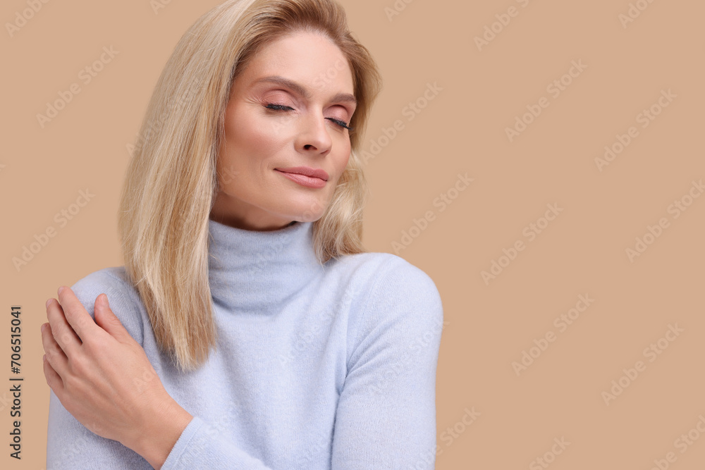 Portrait of beautiful middle aged woman with blonde hair on beige background. Space for text Portrait of beautiful middle aged woman with blonde hair on beige background. Space for text