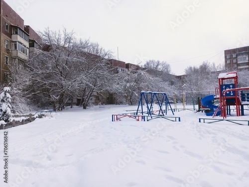 Children's playground in the city during a snowfall in winter.