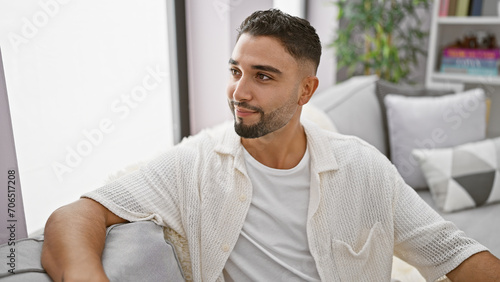 Handsome man with beard in a modern living room looking away thoughtfully.