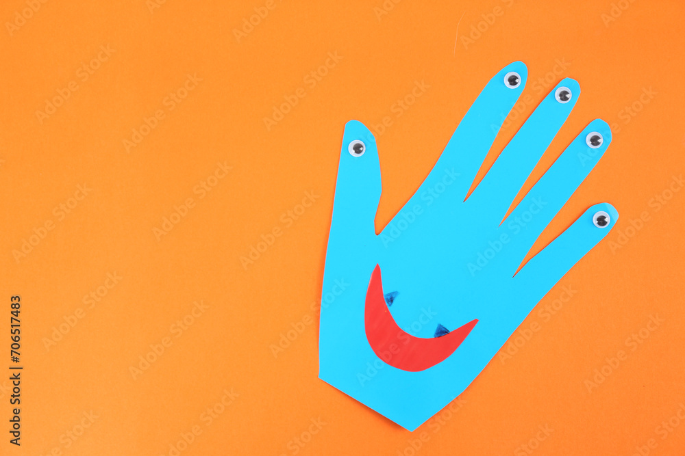 Funny blue hand shaped monster on orange background, top view with space for text. Halloween decoration Funny blue hand shaped monster on orange background, top view with space for text. Halloween decoration