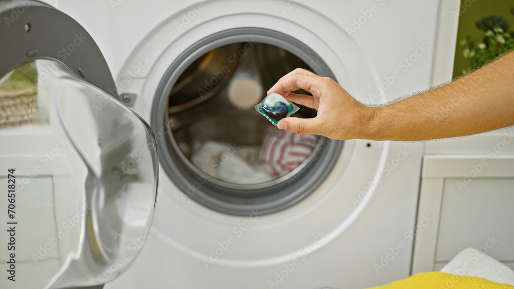 A man uses a laundry pod to wash clothes in a home washing machine, showcasing everyday domestic chores. A man uses a laundry pod to wash clothes in a home washing machine, showcasing everyday domestic chores.