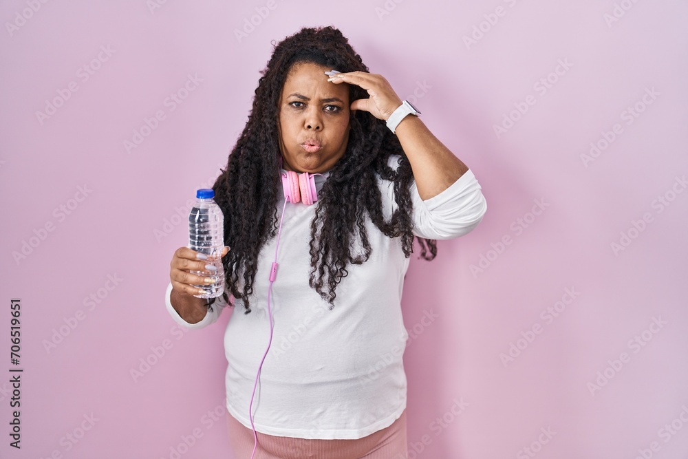 Plus size hispanic woman wearing sportswear and headphones worried and stressed about a problem with hand on forehead, nervous and anxious for crisis Plus size hispanic woman wearing sportswear and headphones worried and stressed about a problem with hand on forehead, nervous and anxious for crisis