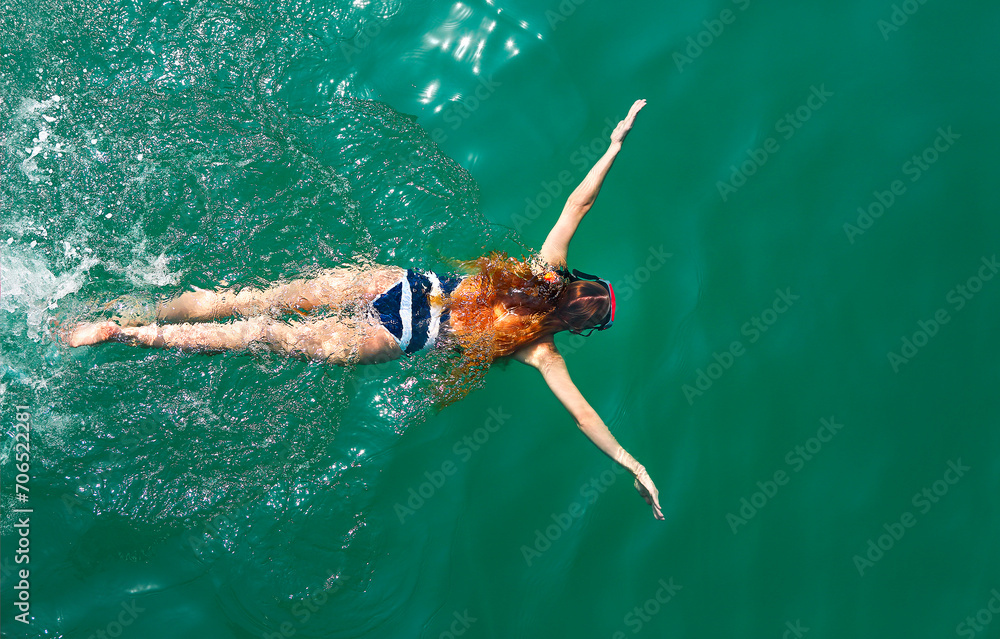 Aerial top down view of a girl wearing swimming mask in the sea