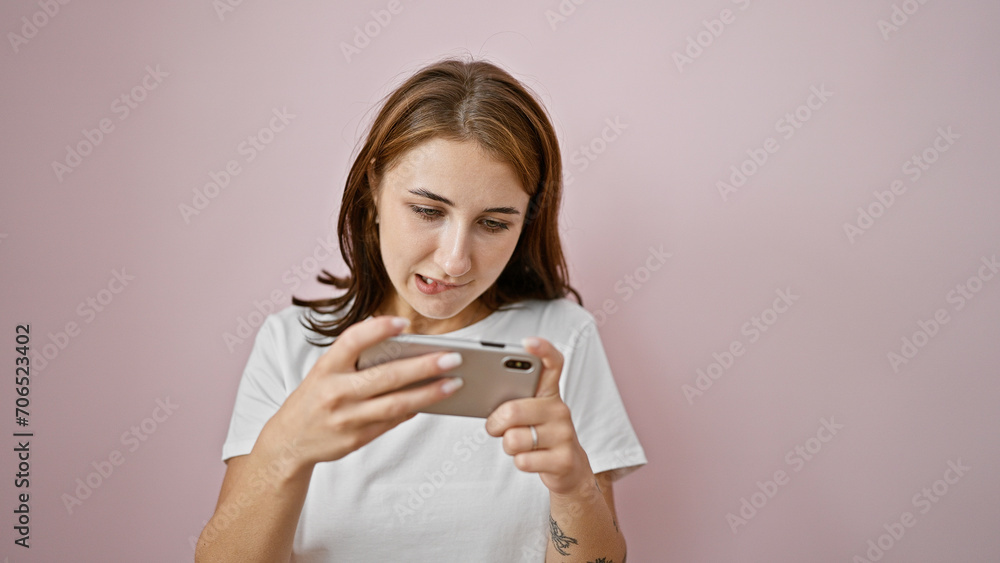 Young woman playing video game over isolated pink background Young woman playing video game over isolated pink background