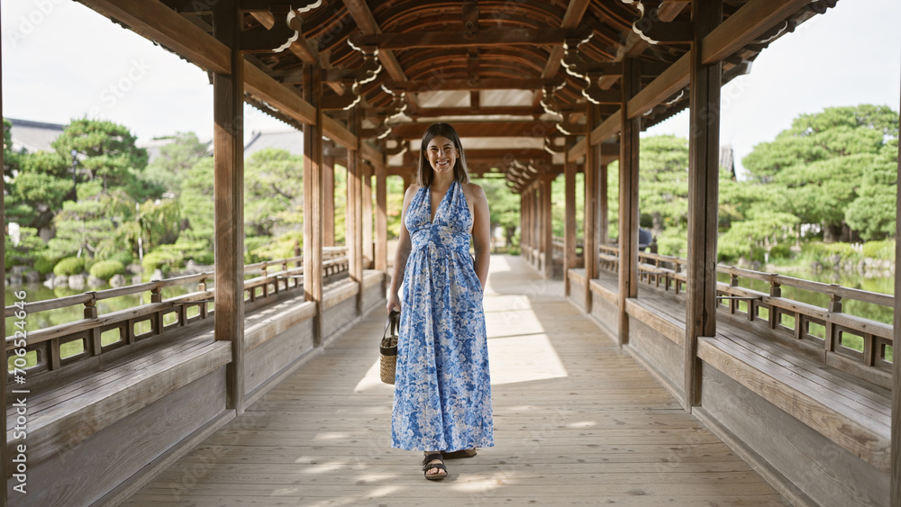 Beautiful hispanic woman radiating joy, confidently posed standing, smiling to the camera while walking to heian jingu in traditional kyoto, japan