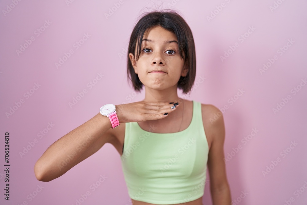 Young girl standing over pink background cutting throat with hand as knife, threaten aggression with furious violence Young girl standing over pink background cutting throat with hand as knife, threaten aggression with furious violence