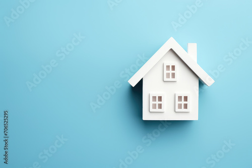 A creatively captured top view of a white house icon on a light blue background, symbolizing key concepts in construction, mortgage, and home loans.