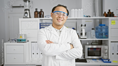 Smiling  confident young chinese man  a pro in science  at his lab station  standing with iconic arms crossed in the epicenter of research and medicine.