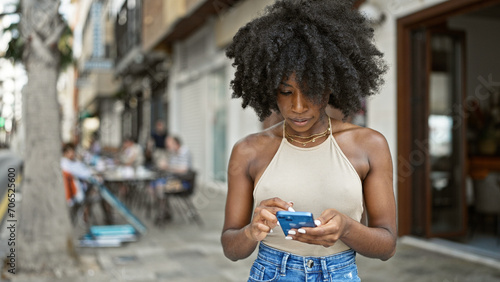 African american woman using smartphone with serious expression at street © Krakenimages.com