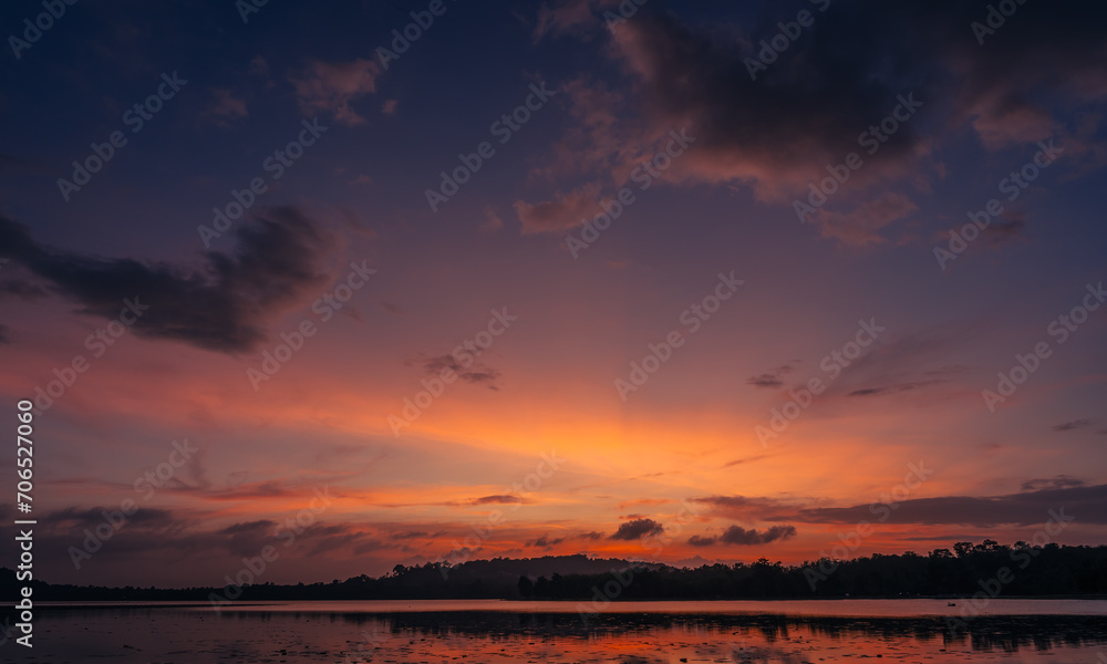Dusk, Sunset sky clouds in the evening on twilight after sundown over silhouette mountain and lake water reflection with orange sunlight in Golden hour, Horizon sky landscape background  